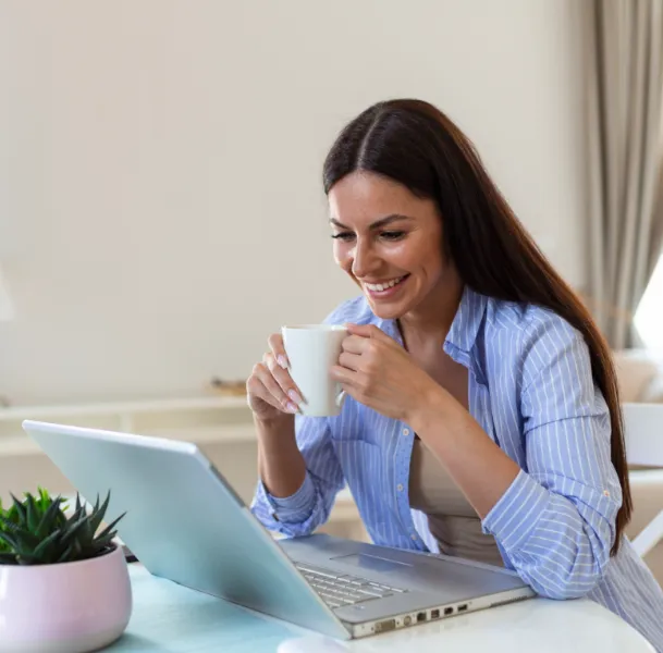 mujer con un portatil y tomandose un cafe